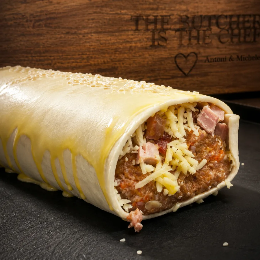 A mega sausage roll cut open, showing ham, bacon and cheese through the mince